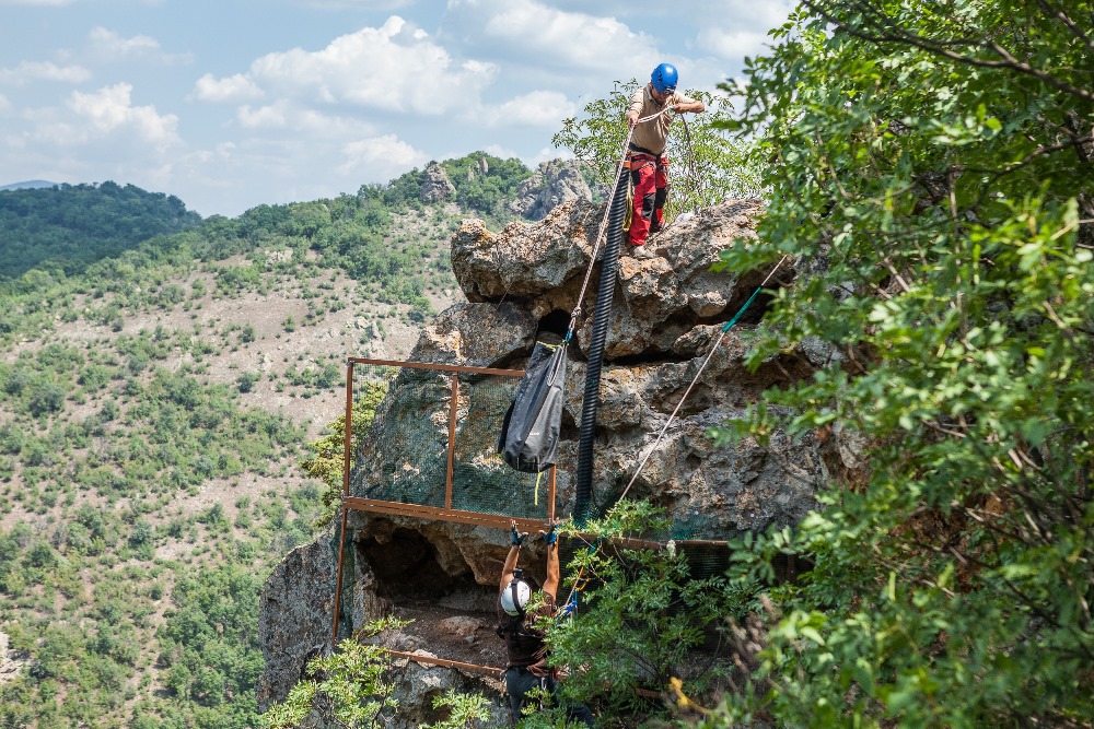 Dobromil Dobrev from BirdLife Bulgaria takes the pouch with the young Egyptian vulture, whose new home will temporarily be this rock nest with stunning views of the Bulgarian mountains and the Arda River. Here you can see the pipe the conservationists will use to feed the chicks. In ten to fourteen days, they will then use a pulley to open the mesh barrier allowing the two females to fly off into the Bulgarian mountains. Photo: Lenka Pastorčáková, Prague Zoo